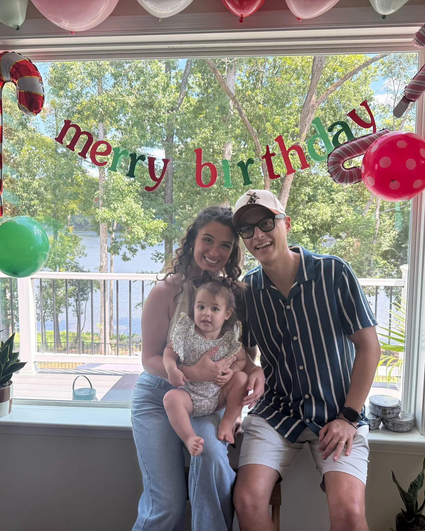 Tyler, Danielle, and Lucia smiling together beneath birthday decorations