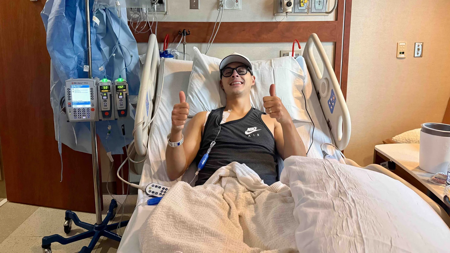 Tyler smiling and giving two thumbs up from a hospital bed