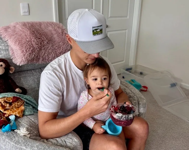 Tyler feeding Lucia a snack while she sits on his lap