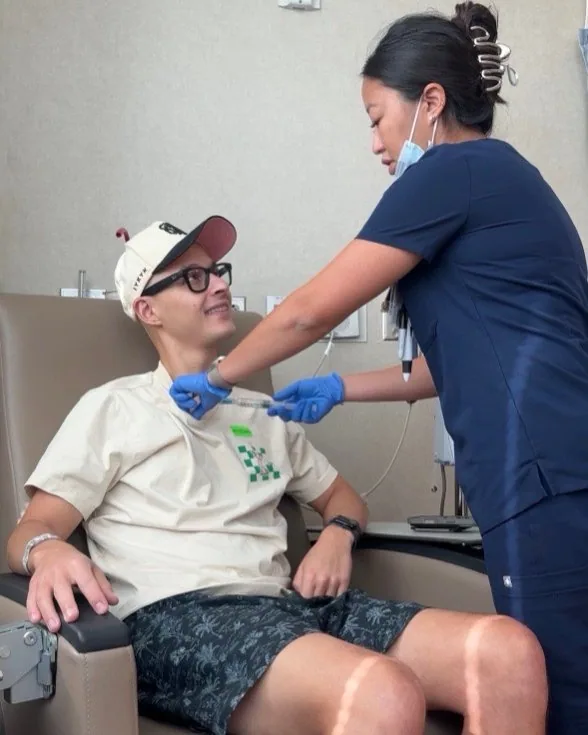 A nurse preparing Tyler for treatment while he smiles from the chair